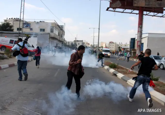 Palestinian protestors run for cover as Israeli forces fire tear gas canisters during clashes following a demonstration calling for the release of prisoners held in Israeli jails and in support of inmates in hunger strik...