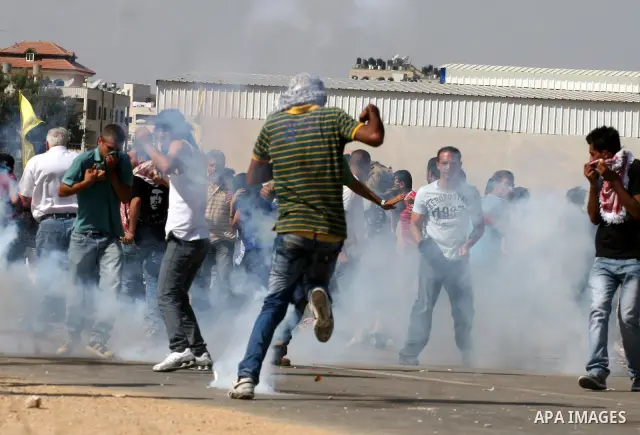 Palestinian protestors run for cover as Israeli forces fire tear gas canisters during clashes following a demonstration calling for the release of prisoners held in Israeli jails and in support of inmates in hunger strik...