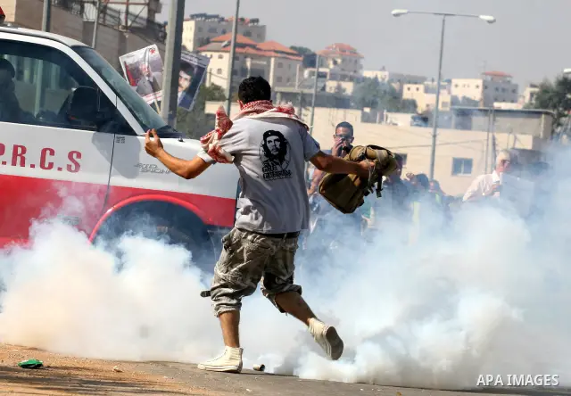 Palestinian protestors run for cover as Israeli forces fire tear gas canisters during clashes following a demonstration calling for the release of prisoners held in Israeli jails and in support of inmates in hunger strik...