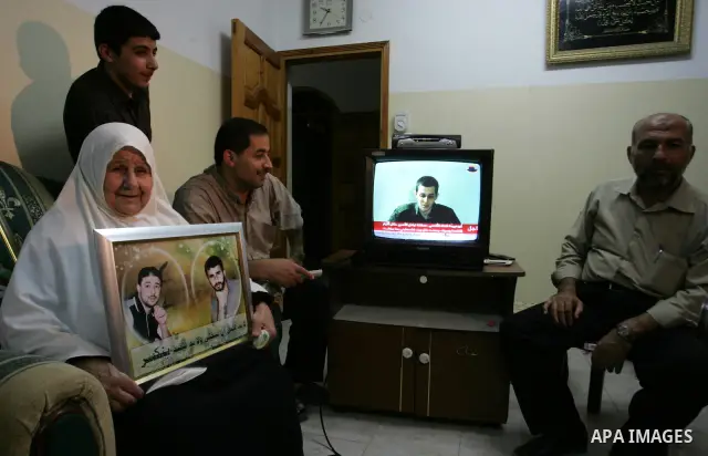The Family of Hassan Salame, watch a television broadcasting the speech of Hamas leader Khaled Meshaal, celebrating a deal that will see Palestinian detainees freed in exchange for Israeli soldier Gilad Shalit, Hassan Sa...
