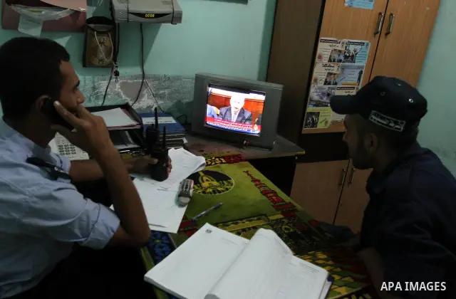 Palestinian Hamas security forces watch a television broadcasting the speech of Hamas leader Khaled Meshaal celebrating a deal that will see Palestinian detainees freed in exchange for Israeli soldier Gilad Shalit on Oct...