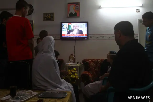 The Family of Mohammed al-Falet, watch a television broadcasting the speech of Hamas leader Khaled Meshaal, celebrating a deal that will see Palestinian detainees freed in exchange for Israeli soldier Gilad Shalit, Moham...