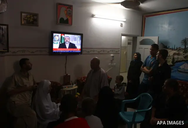 The Family of Mohammed al-Falet, watch a television broadcasting the speech of Hamas leader Khaled Meshaal, celebrating a deal that will see Palestinian detainees freed in exchange for Israeli soldier Gilad Shalit, Moham...
