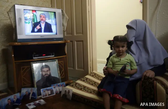 Relatives of Palestinian prisoner Rawhy Mushtaha, held in an Israeli jail, sit in thier house in Gaza City, as they watch a television broadcast of Hamas leader Khaled Meshaal speaking in Damascus, October 11, 2011. Isra...