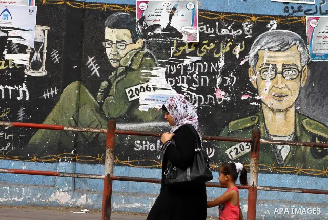 Palestinians walk in front of a wall painting depicting Israeli soldier Gilad Schalit, who is being held in Gaza since he was captured by Hamas-allied militants in a cross-border raid in 2006, in Jebaliya, northern Gaza...