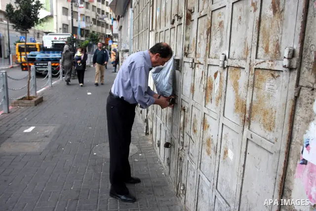 A Palestinian vendor opens a shop following a two-hour strike in solidarity with Palestinian prisoners held in Israeli jails, in the West Bank city of Ramallah, Wednesday, Oct. 12, 2011. According to an Israeli Prison Se...