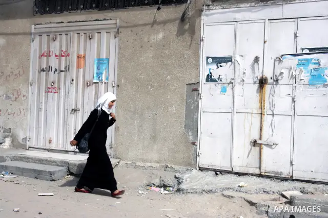 Palestinian schoolgirls walk in front of closed shops following a two-hour strike in solidarity with Palestinian prisoners held in Israeli jails, in Rafah, southern Gaza Strip on October 13, 2011. According to an Israeli...