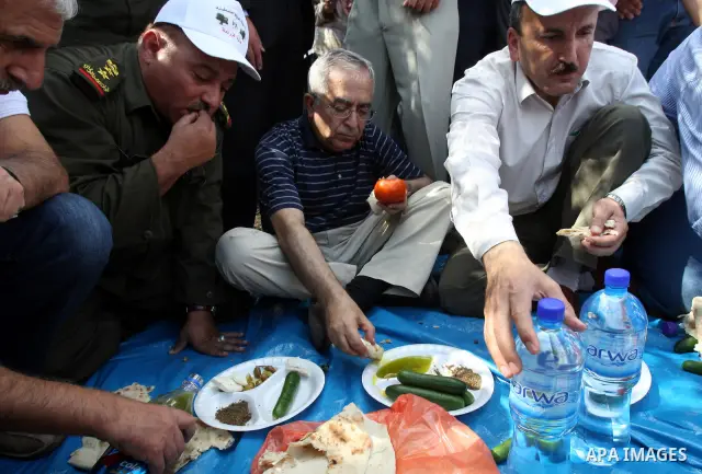 Palestinian Prime Minister Salam Fayyad eat with Palestinian farmers during his visit at the beginning of olive harvest season in the West Bank village of Feraon, near Tulkarem, Thursday, Oct. 13, 2011. A Hamas official...