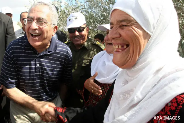 Palestinian Prime Minister Salam Fayyad speaks with Palestinian farmers during his visit at the beginning of olive harvest season in the West Bank village of Feraon, near Tulkarem, Thursday, Oct. 13, 2011. A Hamas offici...
