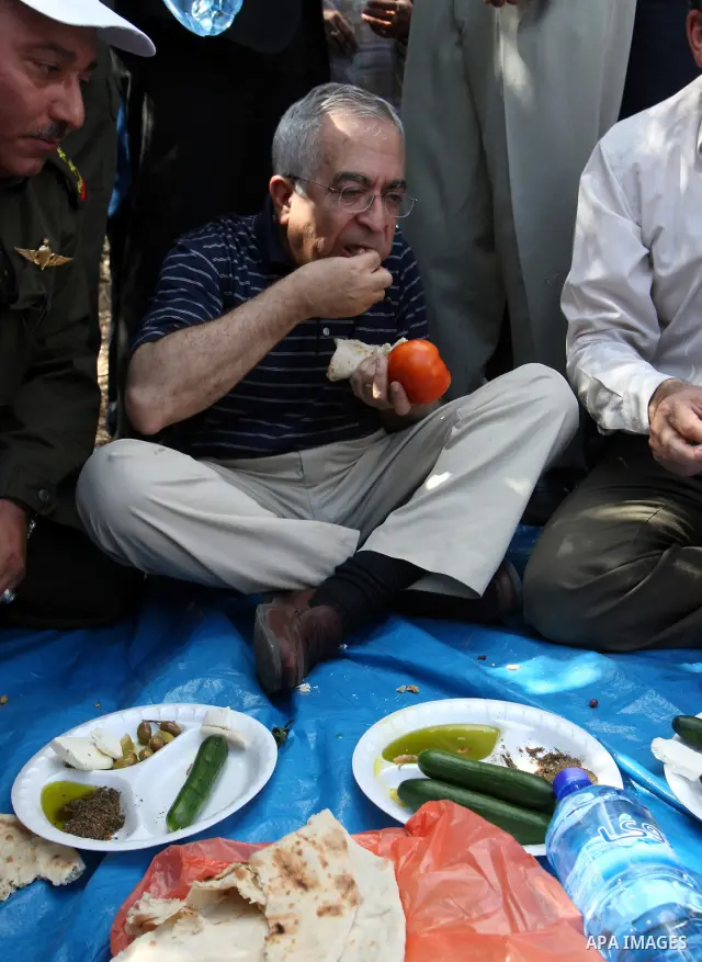 Palestinian Prime Minister Salam Fayyad eat with Palestinian farmers during his visit at the beginning of olive harvest season in the West Bank village of Feraon, near Tulkarem, Thursday, Oct. 13, 2011. A Hamas official...