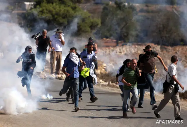 Palestinian, Israeli and foreign activists run away from tear gas canisters fired by Israeli troops during a demonstration against the expansion of the nearby Jewish settlement of Halamish in the West Bank village of Nab...