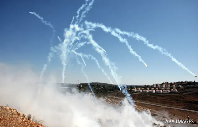 Palestinian, Israeli and foreign activists run away from tear gas canisters fired by Israeli troops during a demonstration against the expansion of the nearby Jewish settlement of Halamish in the West Bank village of Nab...