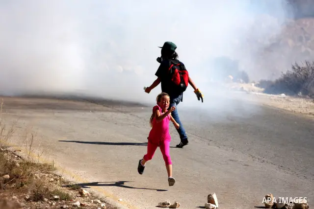 A Palestinian girl runs away from tear gas canisters fired by Israeli troops during a demonstration against the expansion of the nearby Jewish settlement of Halamish in the West Bank village of Nabi Saleh, near Ramallah,...