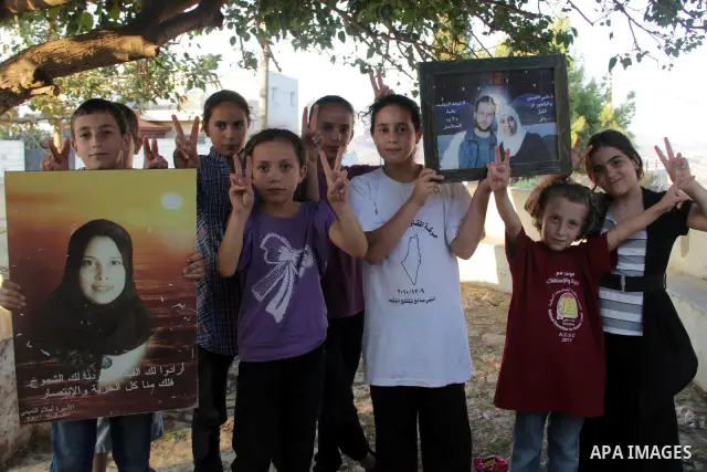 Palestinians from the village of Nabi Saleh celebrate the upcoming release of prisoner Ahlam Tamimi (portrait C-R), imprisoned in an Israeli jail since 2002 and sentenced to 16 life terms for an attack in Jerusalem at th...