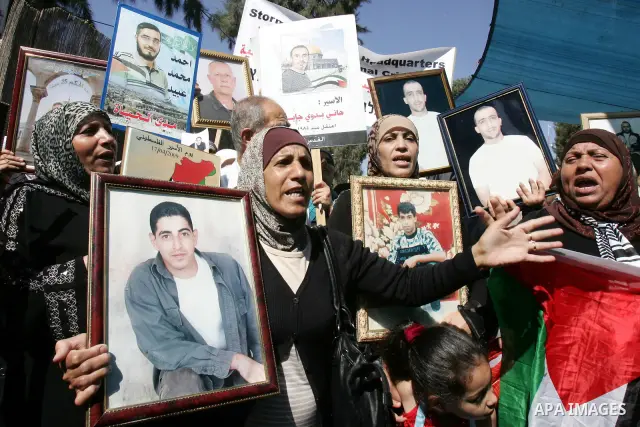 Palestinians hold photographs of their relatives held in Israeli jails during a protest calling for their release, next to the headquarters of the International Red Cross in Jerusalem, October 14, 2011. Israeli soldier G...