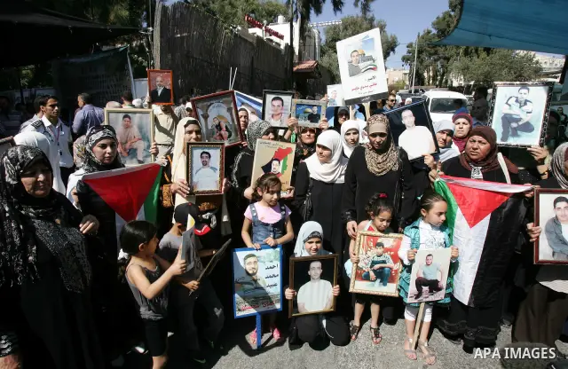 Palestinians hold photographs of their relatives held in Israeli jails during a protest calling for their release, next to the headquarters of the International Red Cross in Jerusalem, October 14, 2011. Israeli soldier G...