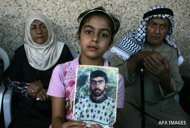 The family of Palestinian prisoner Nasser Nazzal show his picture as they gather at a relative's house in the southern Gaza Strip town of Khan Younis on October 15, 2011 awaiting his release as part of a deal to secure t...