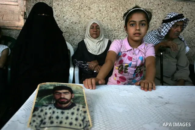 The family of Palestinian prisoner Nasser Nazzal show his picture as they gather at a relative's house in the southern Gaza Strip town of Khan Younis on October 15, 2011 awaiting his release as part of a deal to secure t...