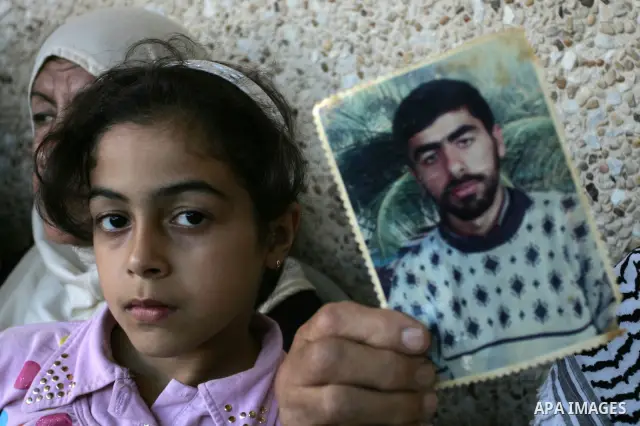 The family of Palestinian prisoner Nasser Nazzal show his picture as they gather at a relative's house in the southern Gaza Strip town of Khan Younis on October 15, 2011 awaiting his release as part of a deal to secure t...