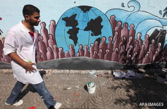 Palestinian artist paints a mural to talk about the challenge of young Palestinians with a high population of the world's 7 billion people in Gaza City, on Oct 16, 2011. Photo by Majdi Fathi