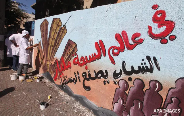 Palestinian artist paints a mural to talk about the challenge of young Palestinians with a high population of the world's 7 billion people in Gaza City, on Oct 16, 2011. Photo by Majdi Fathi