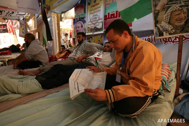 Palestinians look at the lists of Palestinian prisoners, who are to be exchanged for captured Israeli soldier Gilad Schalit, published in the newspapers in Gaza City, Sunday, Oct. 16, 2011. The relatives of Israelis kill...