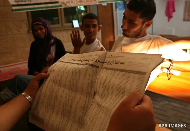 Palestinians look at the lists of Palestinian prisoners, who are to be exchanged for captured Israeli soldier Gilad Schalit, published in the newspapers in Gaza City, Sunday, Oct. 16, 2011. The relatives of Israelis kill...