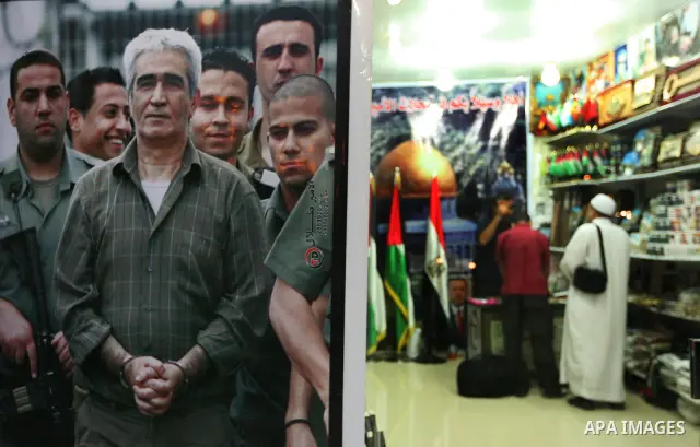A Palestinian vendor displays pictures of Palestinian prisoners held in Israeli jails at his shop in Gaza City, Sunday, Oct. 16, 2011. The relatives of Israelis killed in Palestinian attacks waged a charged debate Sunday...