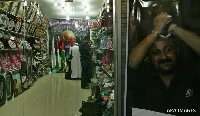 A Palestinian vendor displays pictures of Palestinian prisoners held in Israeli jails at his shop in Gaza City, Sunday, Oct. 16, 2011. The relatives of Israelis killed in Palestinian attacks waged a charged debate Sunday...