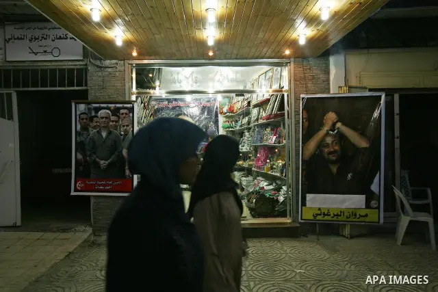 A Palestinian vendor displays pictures of Palestinian prisoners held in Israeli jails at his shop in Gaza City, Sunday, Oct. 16, 2011. The relatives of Israelis killed in Palestinian attacks waged a charged debate Sunday...
