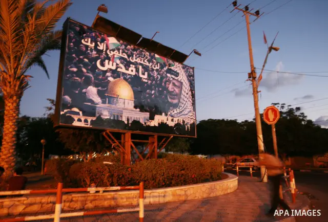A Palestinian man walks past a poster to the late Palestinian president Yasser Arafat in Gaza City, Sunday, Oct. 16, 2011. The relatives of Israelis killed in Palestinian attacks waged a charged debate Sunday over the pl...