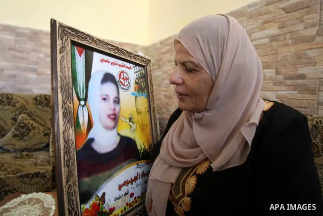 Entesar jayyousi, mother of Palestinian female prisoner doaa jayyousi sentenced to three life sentences in prison Damon , sits next to a photo of her at the family home in the West Bank city of Tulkarem as she reacts to...