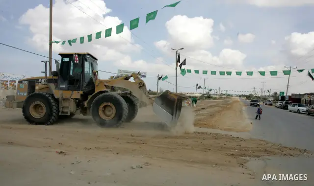 A Palestinian Hamas supporter hangs green Islamic flags as decoration ahead of the upcoming prisoner swap, at the entrance to the Rafah border crossing, southern Gaza Strip, Monday, Oct. 17, 2011. The exchange between Is...