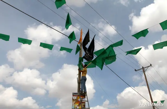 A Palestinian Hamas supporter hangs green Islamic flags at the Rafah border crossing in the southern Gaza Strip October 17, 2011, during preparations for the release of prisoners in a swap that is expected to take place...