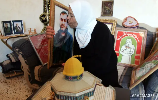 The mother of Palestinian prisoner Adnan Maragha from the east Jerusalem neighbourhood of Silwan, on October 17, 2011, holds a picture of her son, who is among the 1,027 Palestinian prisoners to be freed in exchange for...