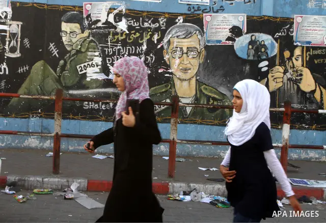 Palestinian girls walk in front of a wall painting depicting captured Israeli soldier Gilad Schalit, in Jebaliya refugee camp, northern Gaza Strip, a day before a prisoner swap between Israel and Hamas, Monday, Oct. 17,...