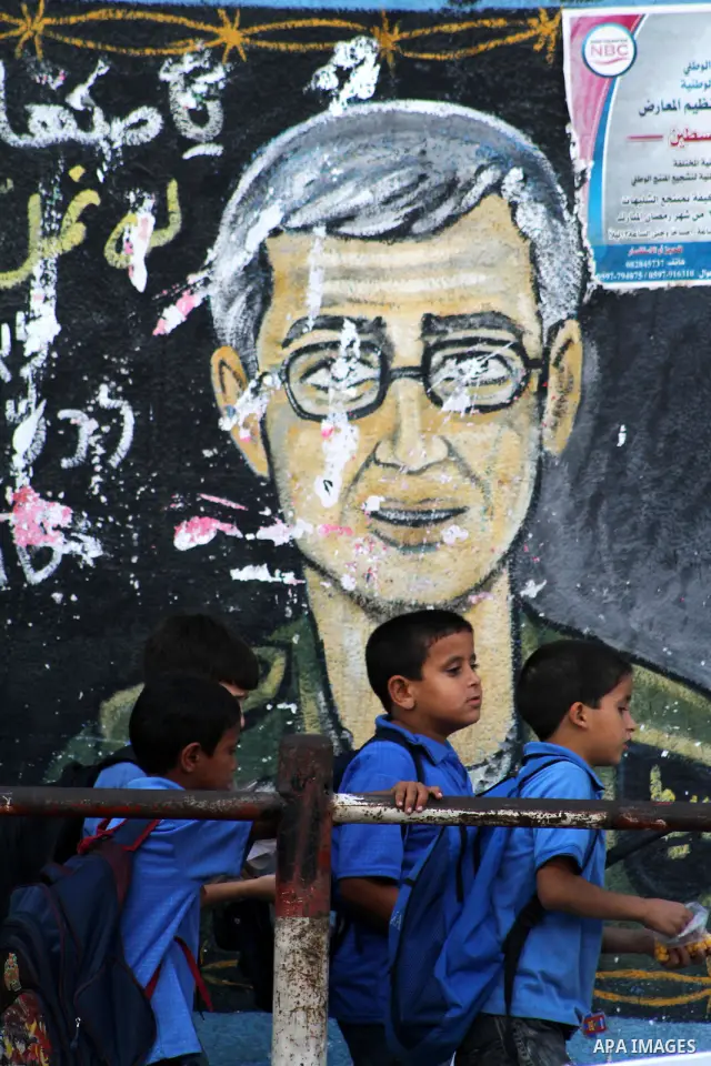 Palestinian boys walk in front of a wall painting depicting captured Israeli soldier Gilad Schalit, in Jebaliya refugee camp, northern Gaza Strip, a day before a prisoner swap between Israel and Hamas, Monday, Oct. 17, 2...