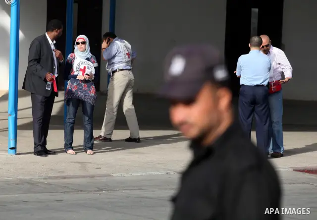 Members of the International Red Cross wait at the Rafah crossing with Egypt in the southern Gaza Strip on October 18, 2011 as an Israeli-Palestinian prisoner swap deal gets under way. Buses carrying 477 Palestinian pris...