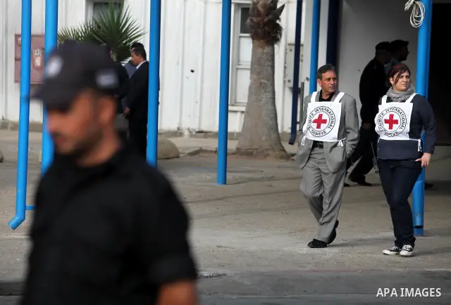 Members of the International Red Cross wait at the Rafah crossing with Egypt in the southern Gaza Strip on October 18, 2011 as an Israeli-Palestinian prisoner swap deal gets under way. Buses carrying 477 Palestinian pris...