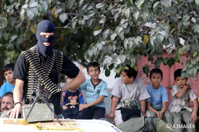 Palestinian boys keep watch as armed Hamas militants stand guard at a street in Gaza city on October 18, 2011 as an Israeli-Palestinian prisoner swap deal gets under way. Buses carrying 477 Palestinian prisoners were hea...
