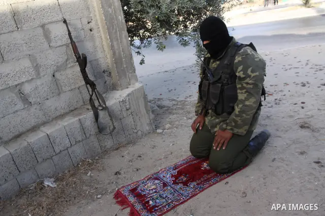 An armed Palestinian Hamas militant prays as he stands guard at a street in Gaza city on October 18, 2011 as an Israeli-Palestinian prisoner swap deal gets under way. Buses carrying 477 Palestinian prisoners were headed...