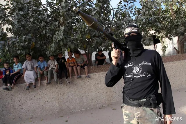 Palestinian boys keep watch as armed Hamas militants stand guard at a street in Gaza city on October 18, 2011 as an Israeli-Palestinian prisoner swap deal gets under way. Buses carrying 477 Palestinian prisoners were hea...