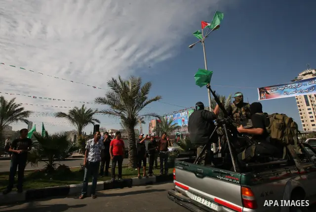 Palestinians keep watch as Hamas militants stand guard in Gaza City on October 18, 2011 as an Israeli-Palestinian prisoner swap deal gets under way. Captive Israeli soldier Gilad Shalit was today freed from five years of...