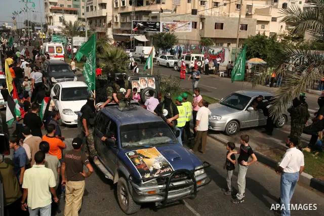 Palestinians keep watch as Hamas militants stand guard in Gaza City on October 18, 2011 as an Israeli-Palestinian prisoner swap deal gets under way. Captive Israeli soldier Gilad Shalit was today freed from five years of...