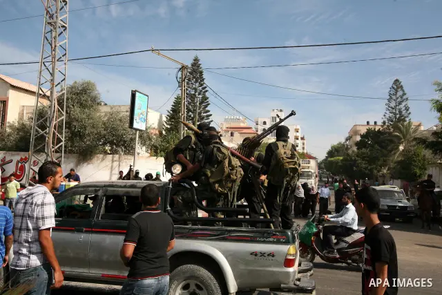 Palestinians keep watch as Hamas militants stand guard in Gaza City on October 18, 2011 as an Israeli-Palestinian prisoner swap deal gets under way. Captive Israeli soldier Gilad Shalit was today freed from five years of...