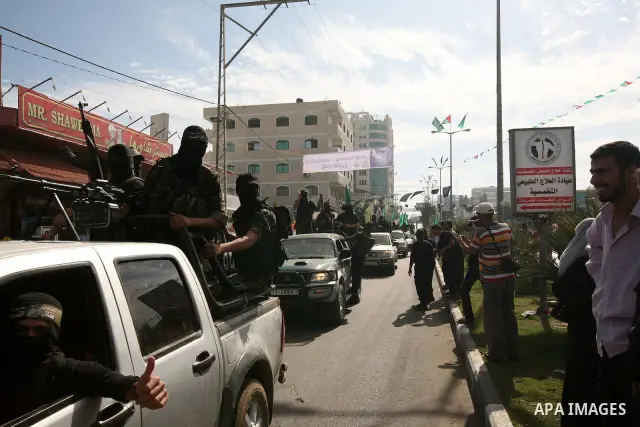 Palestinians keep watch as Hamas militants stand guard in Gaza City on October 18, 2011 as an Israeli-Palestinian prisoner swap deal gets under way. Captive Israeli soldier Gilad Shalit was today freed from five years of...