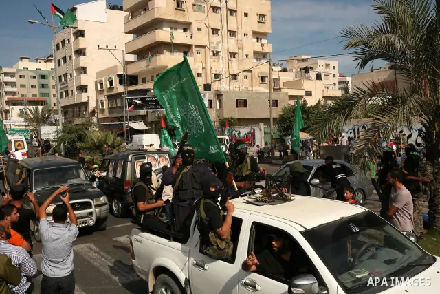 Palestinians keep watch as Hamas militants stand guard in Gaza City on October 18, 2011 as an Israeli-Palestinian prisoner swap deal gets under way. Captive Israeli soldier Gilad Shalit was today freed from five years of...