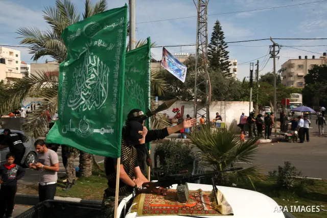 Palestinians keep watch as Hamas militants stand guard in Gaza City on October 18, 2011 as an Israeli-Palestinian prisoner swap deal gets under way. Captive Israeli soldier Gilad Shalit was today freed from five years of...