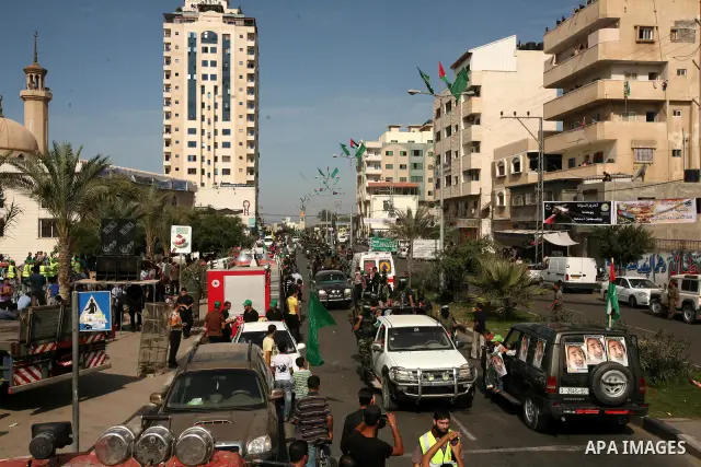Palestinians keep watch as Hamas militants stand guard in Gaza City on October 18, 2011 as an Israeli-Palestinian prisoner swap deal gets under way. Captive Israeli soldier Gilad Shalit was today freed from five years of...