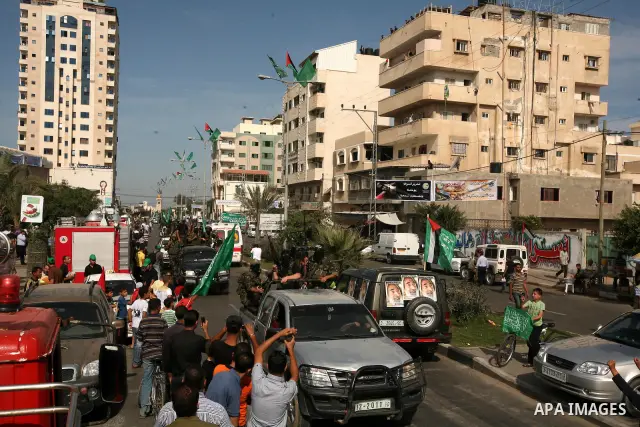 Palestinians keep watch as Hamas militants stand guard in Gaza City on October 18, 2011 as an Israeli-Palestinian prisoner swap deal gets under way. Captive Israeli soldier Gilad Shalit was today freed from five years of...